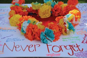 Students signed a poster with a heart cutout filled with paper flowers at the "Remember the 17" walkout. The sign includes statements such as "Never Forget" and "May your beautiful souls rest in paradise" meant to honor the 17 lives lost in the Stoneman Douglas High School shooting. Photo credit to Jazzminn Morecraft