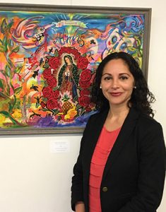 Professor Georgina Guzman poses in front of artwork at an event. On March 9, Professor Guzman was recognized by the California Association of Teachers of English and won an award for college classroom excellence. Photo credit to CSUCI.