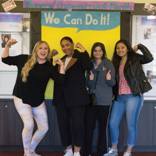 Students pose in front of a "We Can Do It!" poster in the Student Union. The poster, along with photos of women throughout history, were set up in the Student Union to celebrate Women's History Month. Photo credit to Dennys Rico.