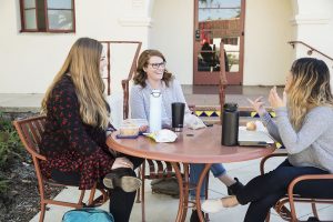 Three students sit around a table and enjoy a meal while they converse with one another. Photo credit to CI Communication and Marketing.